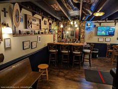 the inside of a bar with wooden tables and stools