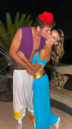 a man and woman dressed in costumes standing next to each other on a patio at night