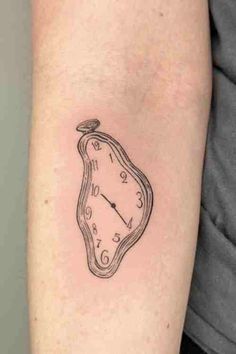 a small clock tattoo on the left inner arm, which is drawn in black ink