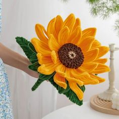 a woman holding a fake sunflower in her hand