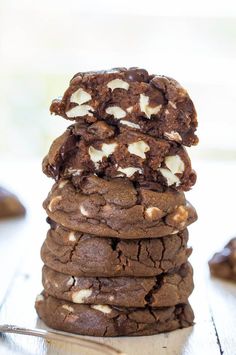 a stack of cookies with white chocolate chips and marshmallows on top, sitting on a plate