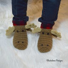 a pair of crocheted moose slippers on top of a white fur rug