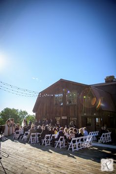 a group of people that are sitting in chairs on a wooden floor near a building