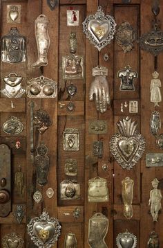 an assortment of metal items on display in a wooden wall with many different shapes and sizes