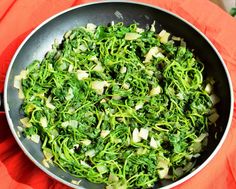 a pan filled with green vegetables on top of a red cloth