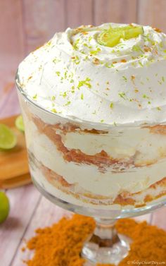 a layered dessert in a glass dish with limes on the side and cinnamon sprinkles around it