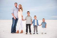 a family standing in the sand holding hands