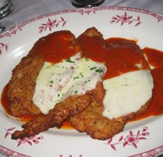 two fried meat patties covered in sauce and gravy on a floral plate