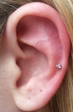 a woman's ear with a single diamond in it