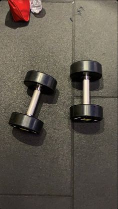 two dumbbells sitting on the floor next to each other