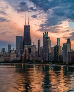 the city skyline is reflected in the water at sunset with clouds and reflections on the water