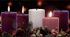 three candles are sitting in the middle of some christmas tree branches with ornaments around them