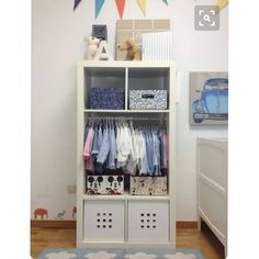 a white bookcase filled with clothes next to a dresser and bed in a child's room