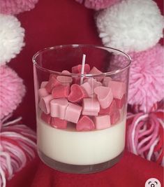 a glass filled with marshmallows sitting on top of a red blanket next to pink and white teddy bears