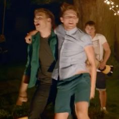 three young men standing next to each other in front of a tree with sparklers