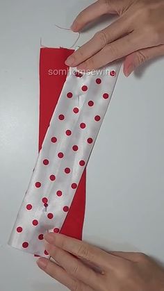 two hands that are holding something on a white surface with red polka dots and one hand is pulling it out