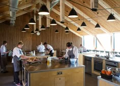 some people are preparing food in a large wooden room with many lights hanging from the ceiling