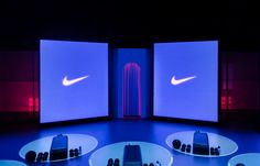 four white plates with nike logos on them in front of three large screen screens that are lit up