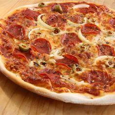 a pizza with pepperoni and onions on a wooden table