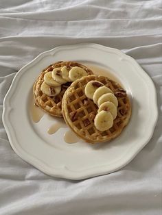 two waffles with banana slices on a white plate