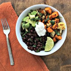 a white bowl filled with black beans, avocado and sour cream