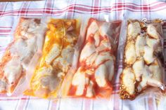 four pieces of food wrapped in plastic sitting on a checkered table cloth, ready to be eaten