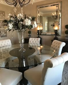 a dining room table with white chairs and a chandelier