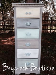 an old dresser has been painted white and gray with silver hardware on the bottom drawer