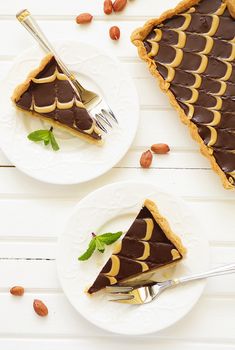 two plates with slices of chocolate tart pie on top of white wooden planks