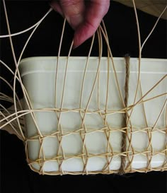 a person is holding a white bowl with many strings on it