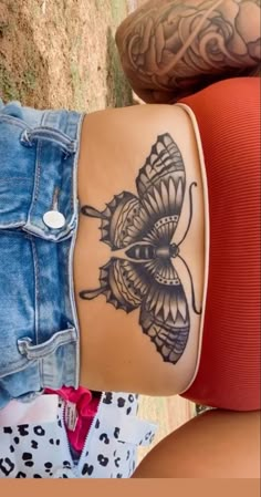 two people with tattoos on their stomachs and one has a butterfly tattooed on it