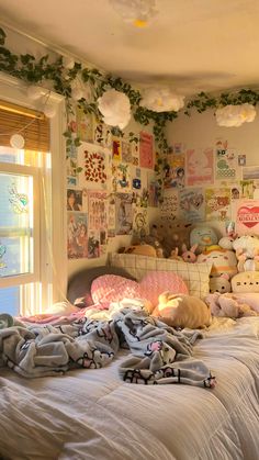 an unmade bed with lots of stuffed animals on the wall and pillows in front of it