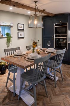 a dining room table with chairs and plates on it in the middle of a kitchen