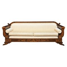 an antique wooden couch with white upholstered fabric