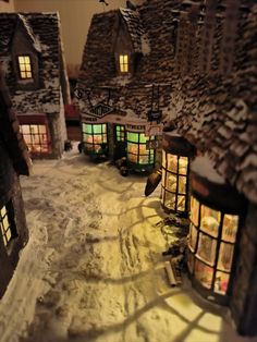 an image of a snow covered village with lights on it's windows and doors