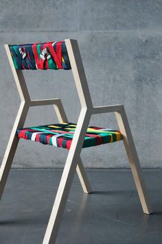 a colorful chair sitting in front of a concrete wall