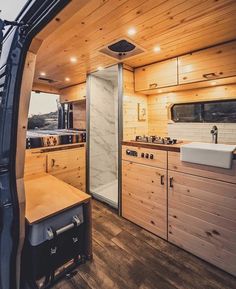 the inside of a camper with wood paneling and white sink, cabinets, and counter tops