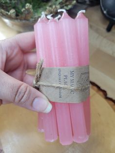 a person holding three pink candles in their hand with a tag on the top one