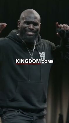 a man in a black hoodie is smiling and raising his hands with the words kingdom come above him