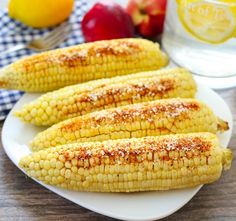 grilled corn on the cob with seasoning and lemons in the background