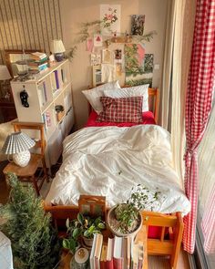 a bed sitting next to a window with lots of plants on top of it in a bedroom