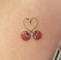 two cherries in the shape of a heart on the back of a woman's arm