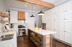 a kitchen with white cabinets and an island in the middle, surrounded by wood flooring