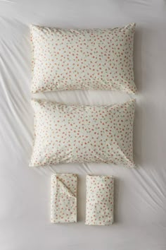 a bed with white sheets and pillows on top of it next to two pillow cases