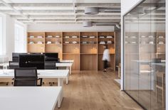 an empty office with lots of desks and chairs in front of glass walls that have shelves on them