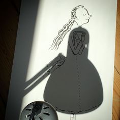 the shadow of a woman's dress on a paper cutout next to a clock