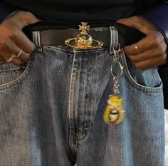 a woman is holding onto her jeans and has a gold lion keychain on it