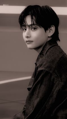 a black and white photo of a person wearing a jean jacket with his hair pulled back