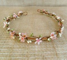 a headband with pink flowers and leaves on top of a tan tablecloth covered floor