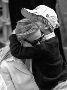 black and white photograph of a woman kissing a man's head with sunglasses on